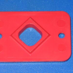 A red plastic 4 way actuator plate with holes on it.
