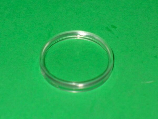 A Gun Lens plastic ring on a green surface.
