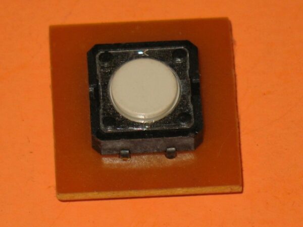 A small white 839-0016 Board, Switch, Laser Ghost on an orange piece of paper.