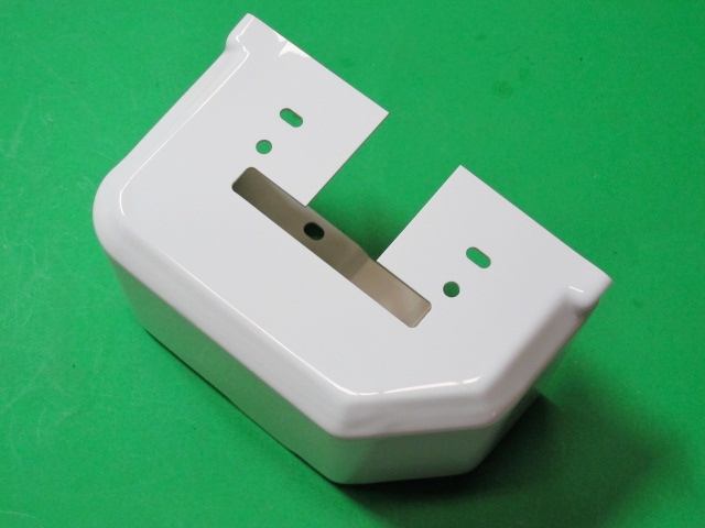 A white plastic Throttle Cover on a green surface.