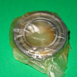 A 100-5063 ball bearing in a plastic bag on a green surface.
