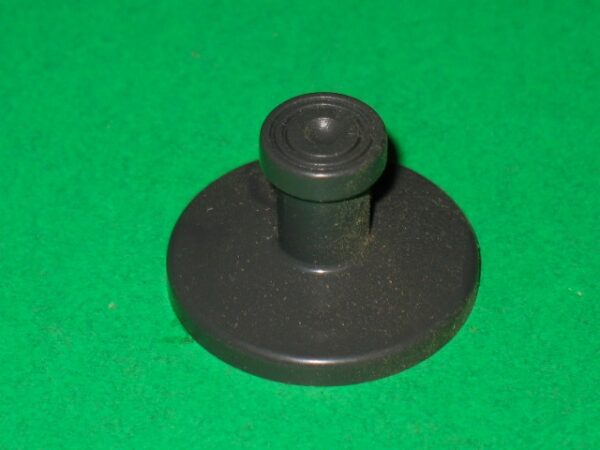 A black joystick on a green surface.