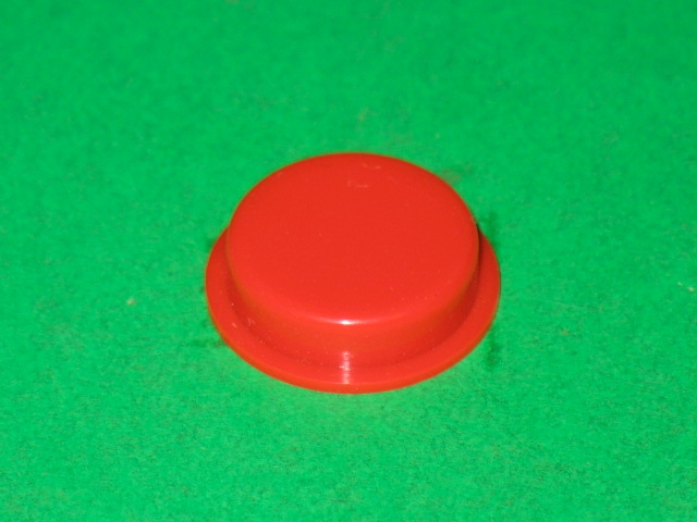 A red plastic Cast switch on a green surface.