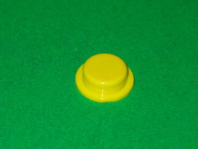 A yellow plastic Cap on a green surface.