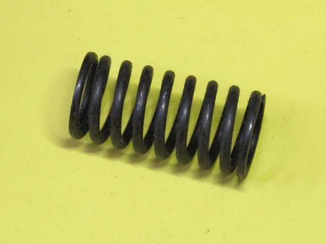 A Virtua Racing Pedal Spring on a yellow surface.