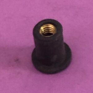 A black plastic well nut on a purple surface.