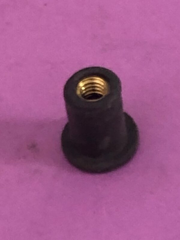 A black plastic well nut on a purple surface.