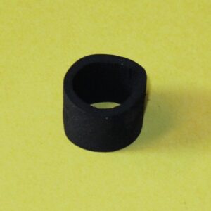 A black rubber bushing on a yellow surface.