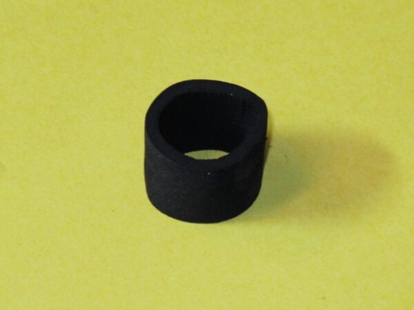 A black rubber bushing on a yellow surface.