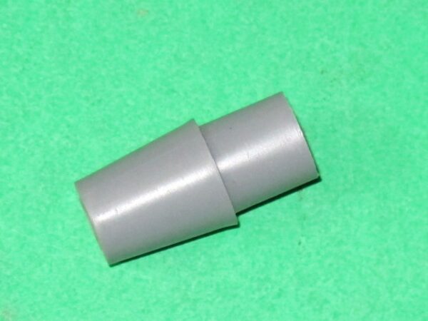 A gray plastic 4 way actuator for shaft on a green surface.