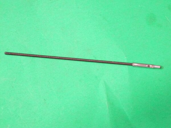 A metal rod on a green surface. 
Product Name: Accel cable, Ride On cabinet

Revised Sentence: An accel cable and Ride On cabinet on a green surface.