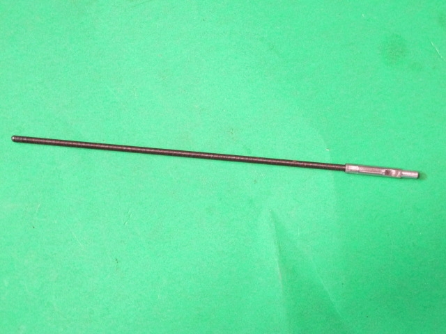 A metal rod on a green surface. 
Product Name: Accel cable, Ride On cabinet

Revised Sentence: An accel cable and Ride On cabinet on a green surface.