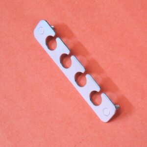 A bracket with four holes on an orange surface.