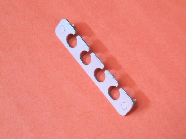 A bracket with four holes on an orange surface.