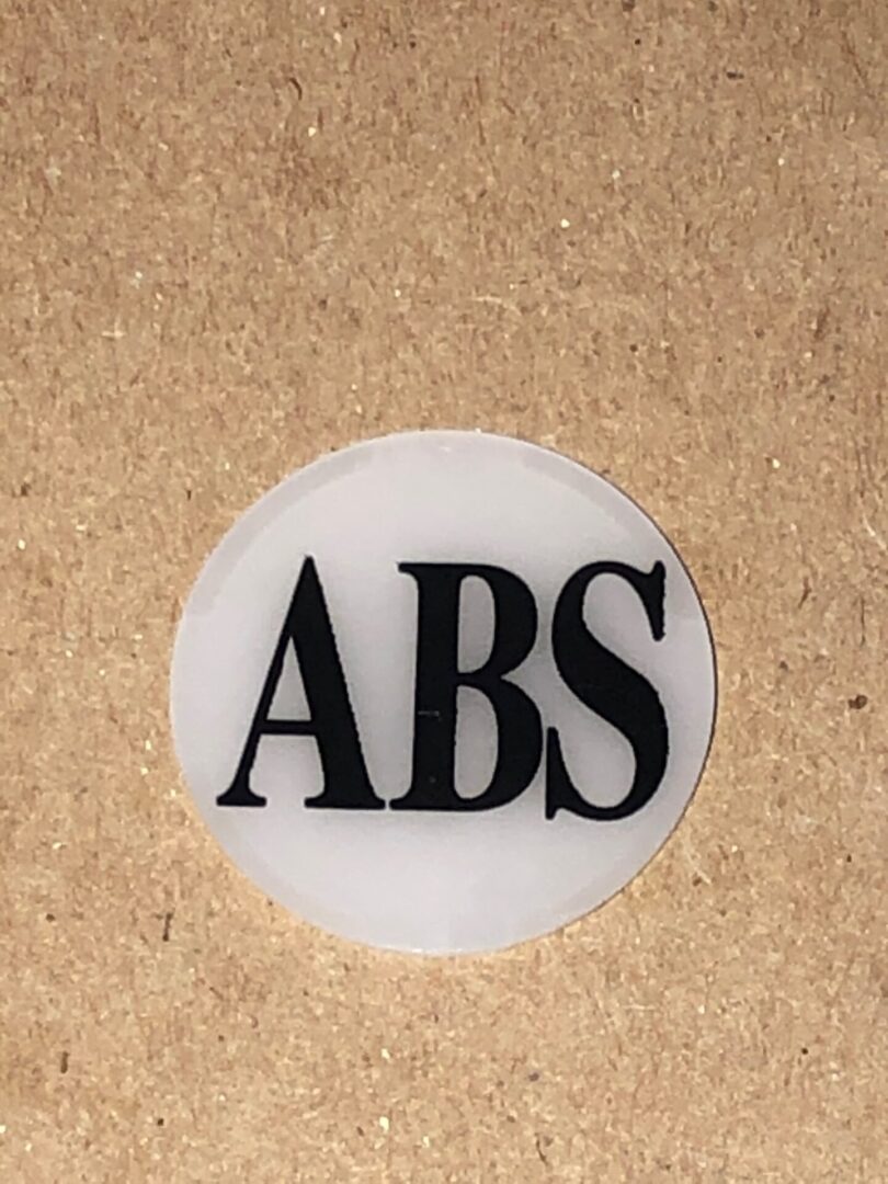 A ABS Button Cover sticker with the word abs on it.