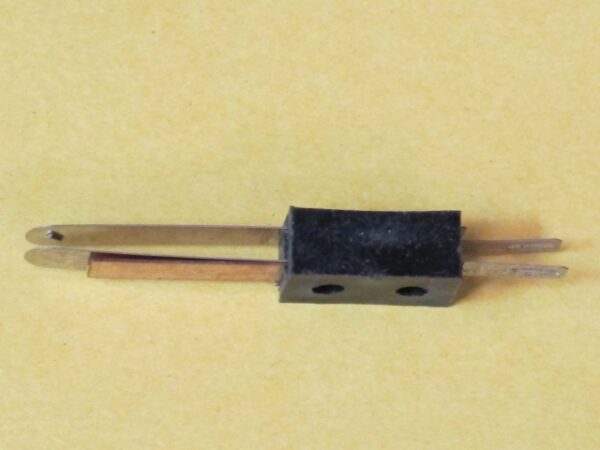 A small piece of Wico Leaf Switch, Cross Contacts on a yellow background.