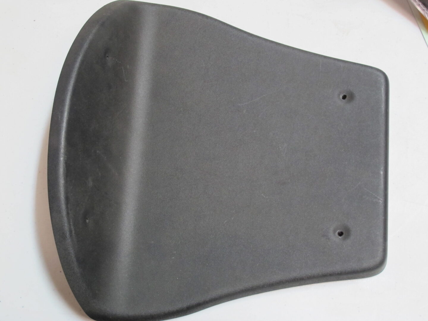 A black NOS Seat plastic, GP Rider cover on a table.