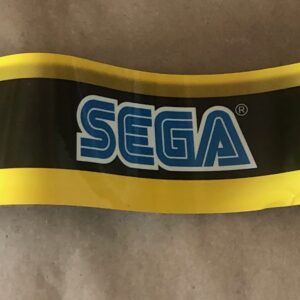 A yellow and black Sega logo sticker on a piece of paper.