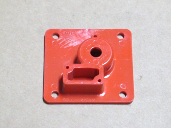 An orange plastic housing with a hole in it.