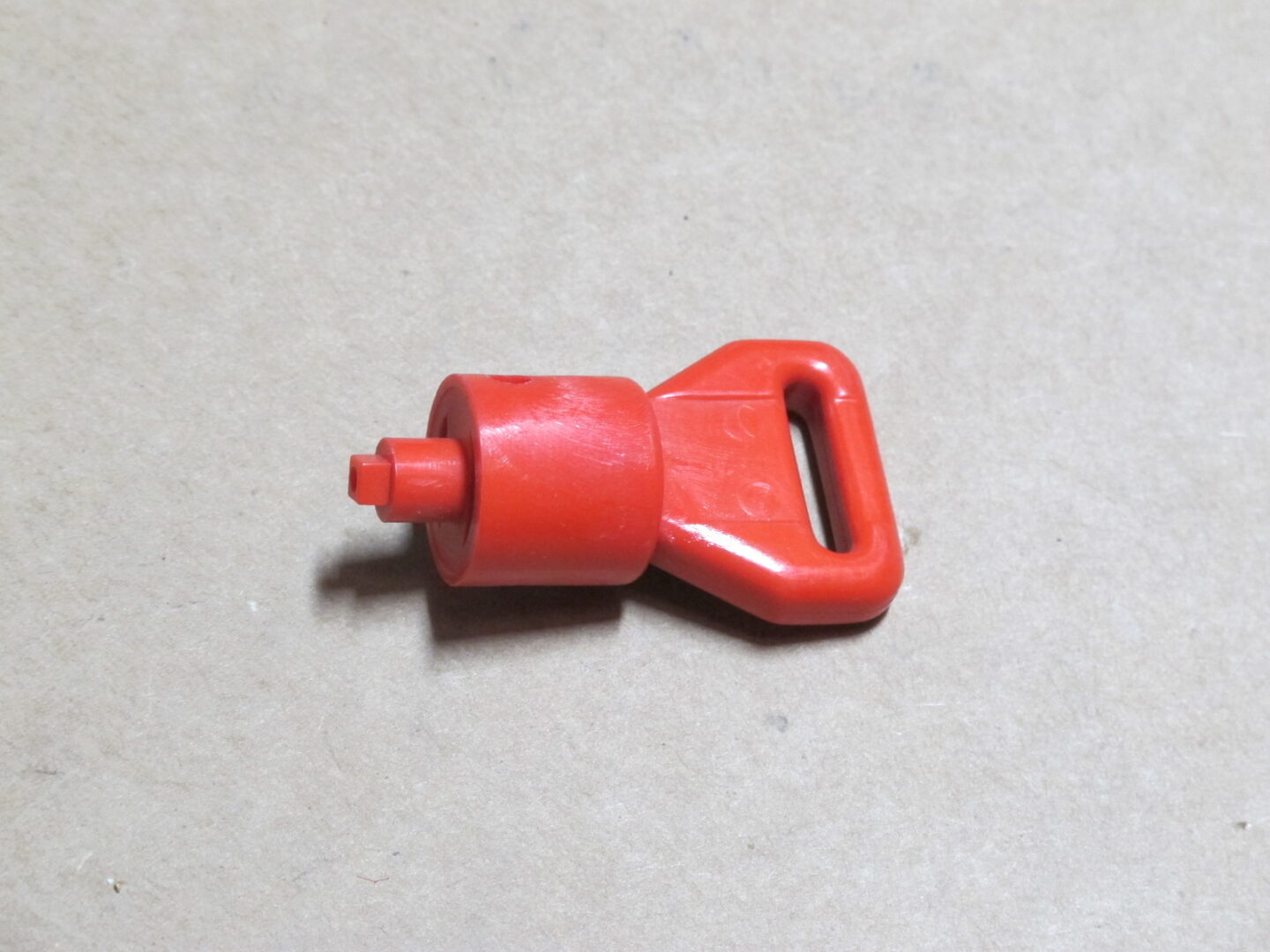 A small Key Plastic, Red handle on a table.