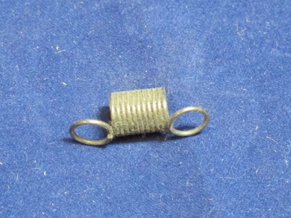 A small Brake Spring on a blue surface.