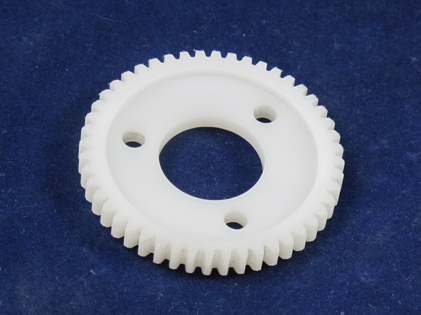 A white clutch gear on a blue surface.