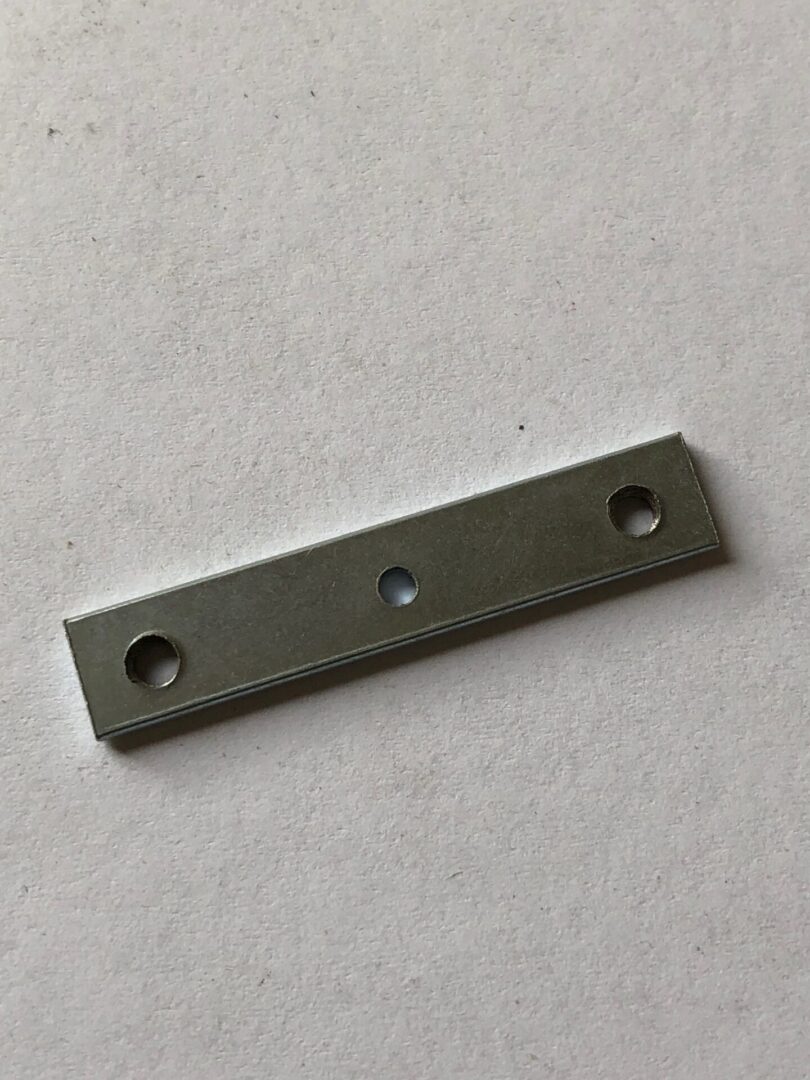 A black metal object with three holes.