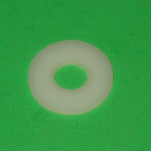 A white plastic washer on a green surface.