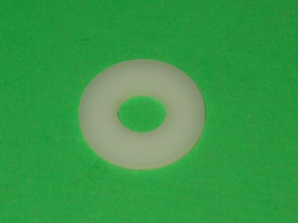 A white plastic washer on a green surface.