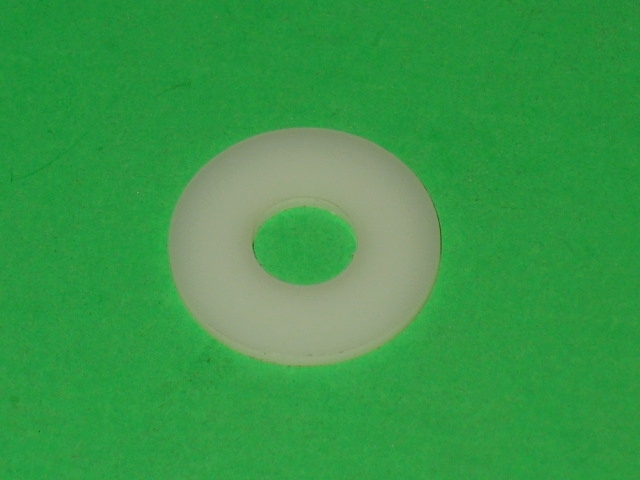 A white plastic washer on a green surface.