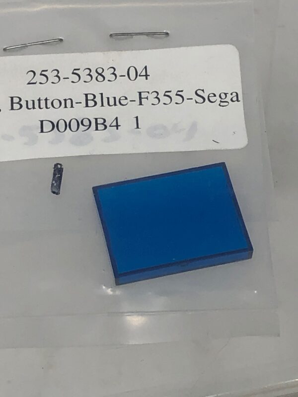 A Blue F355 button is in a package with a piece of plastic.