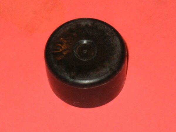 A black Tube Cap on a red surface.