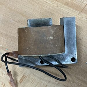 Close-up of an old electrical transformer with wires on a wooden surface.