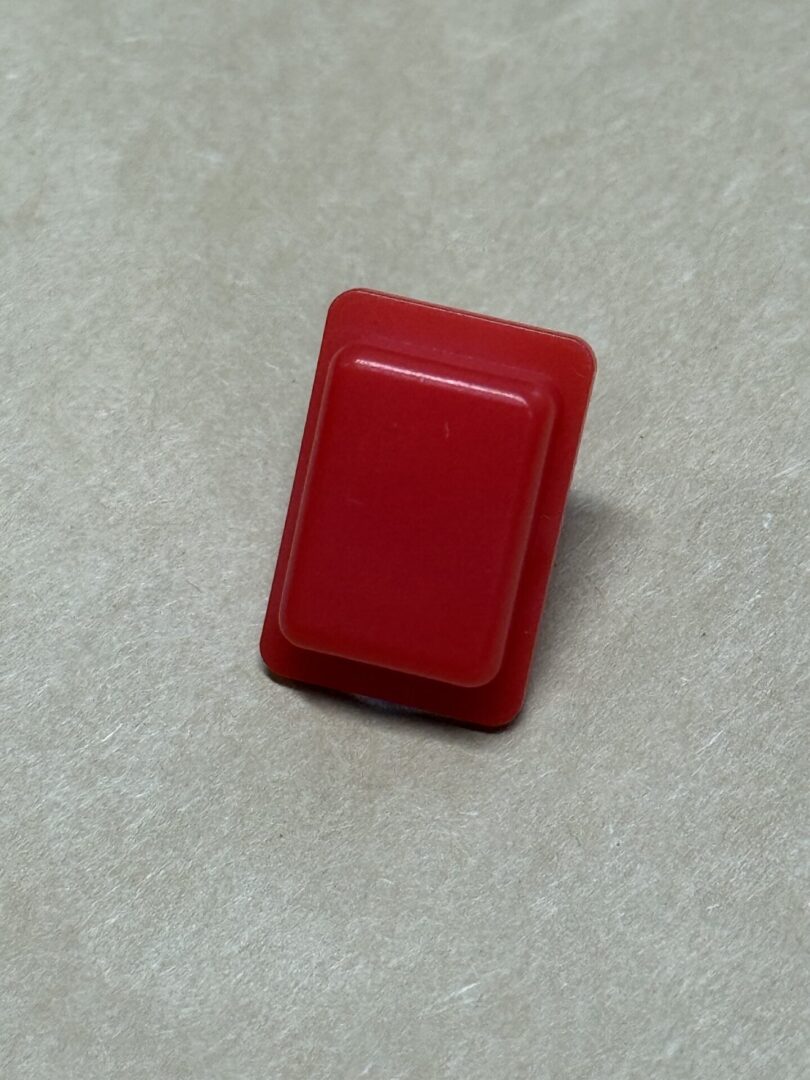 A red rectangular button on a light surface.