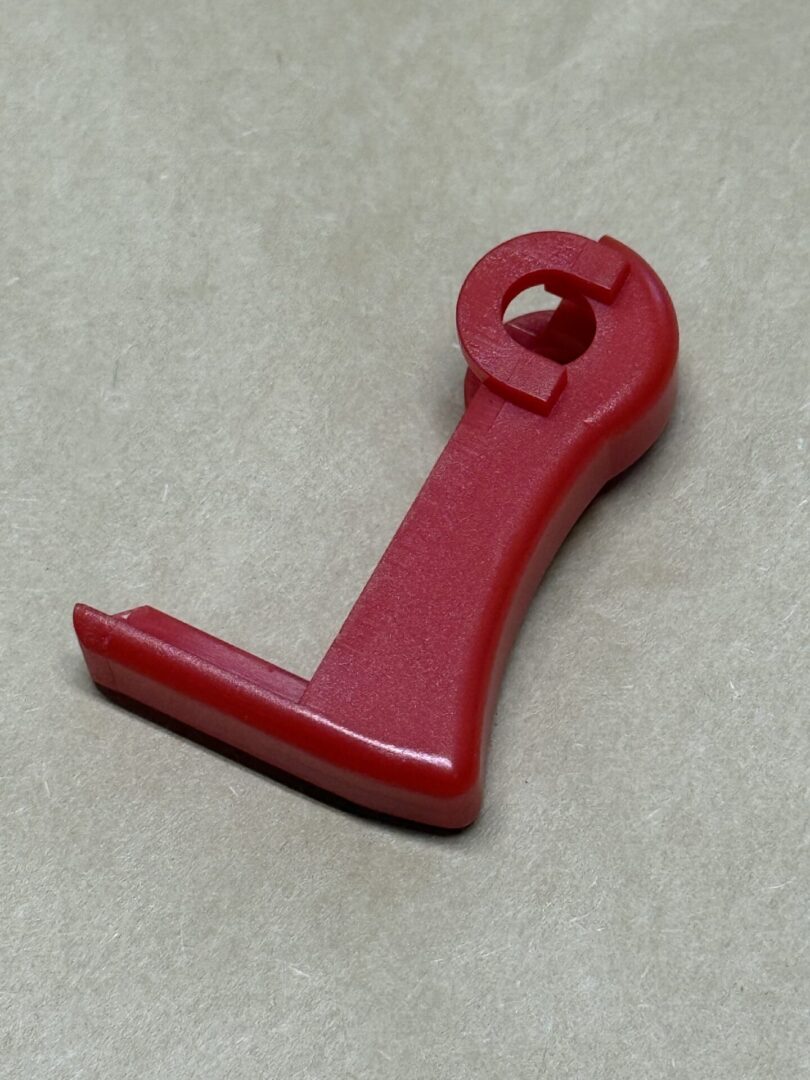 Red plastic tool with a hexagonal hole and flat base.