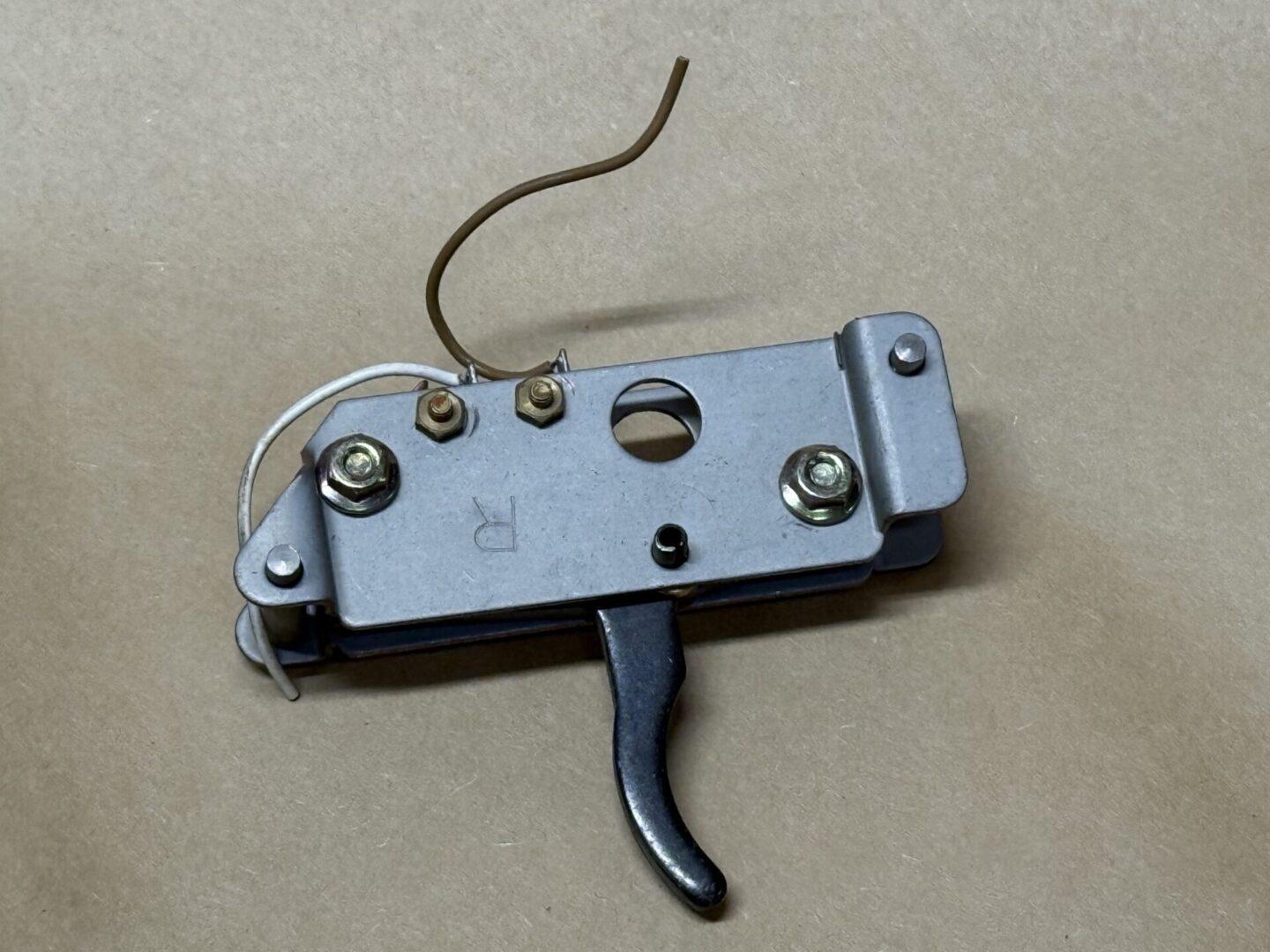 Close-up of a mechanical trigger mechanism with wires and screws.